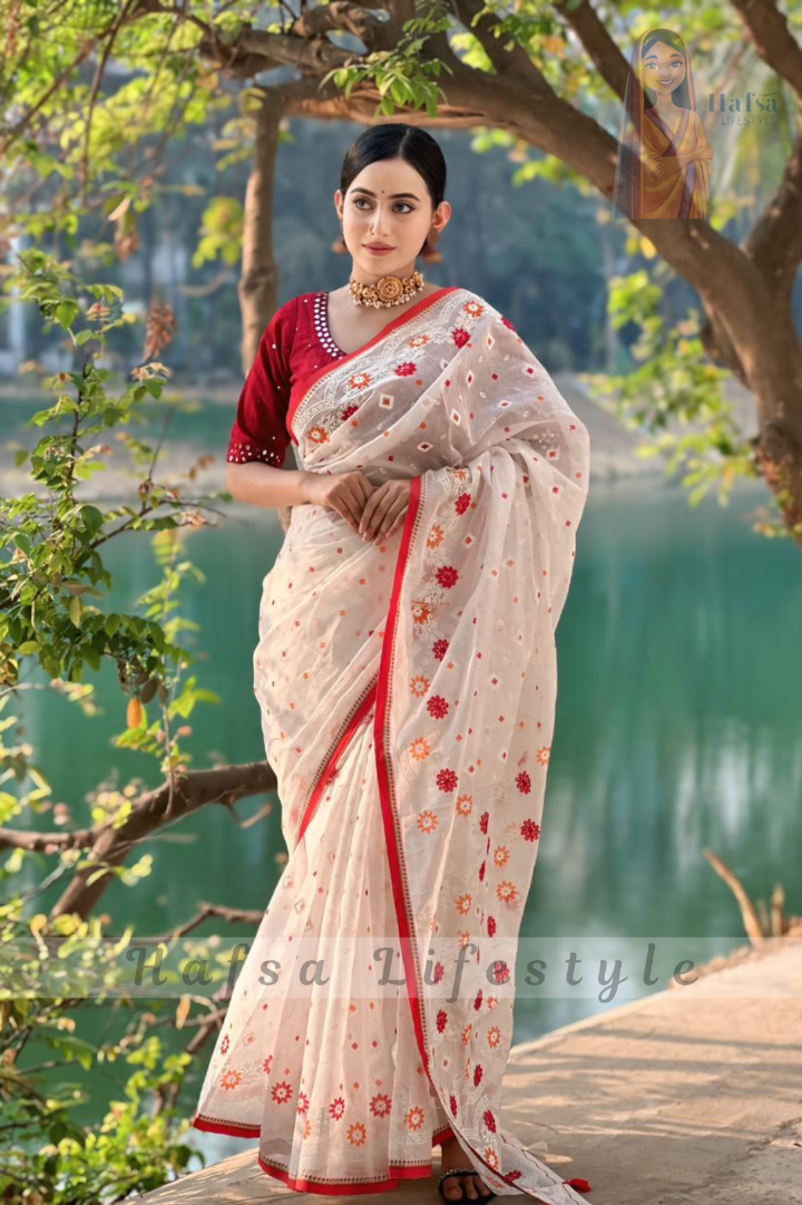 Woman in a saree standing by a lake with trees in the background